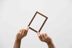 Free photo hands holding small wooden frame