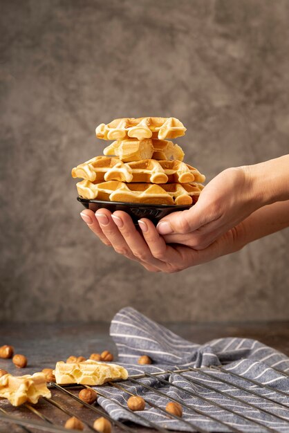 Hands holding stack of waffles on plate