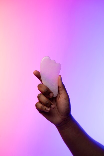 Hands holding stone made instrument over gradient background