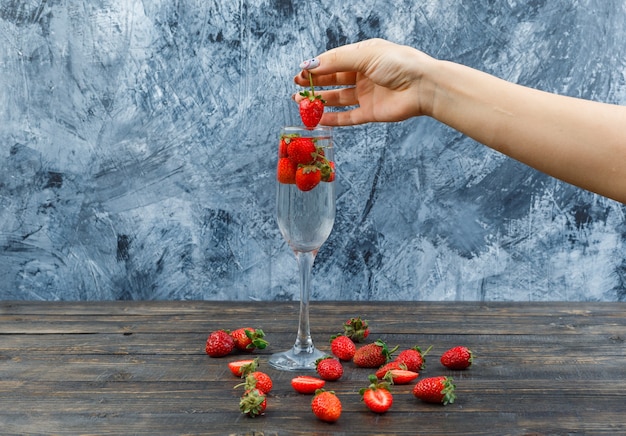 Free photo hands holding strawberries on wooden board