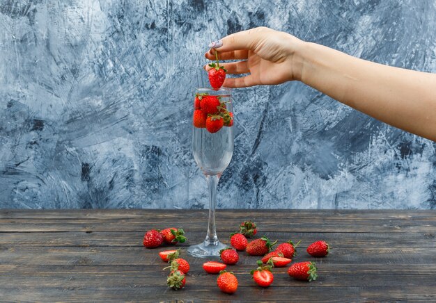 Hands holding strawberries on wooden board