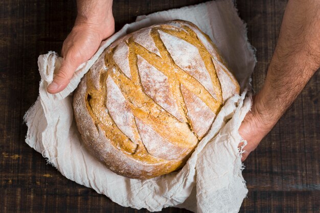 Hands holding tasteful bread wrapped in cloth