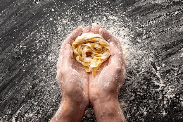 Free photo hands holding uncooked tagliatelle