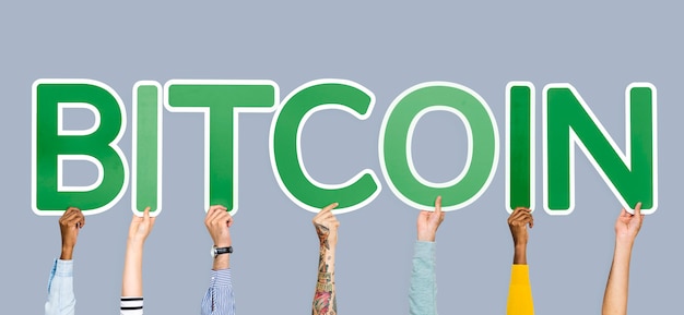 Hands holding up green letters forming the word bitcoin