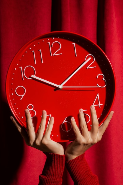 Free photo hands holding wall clock still life