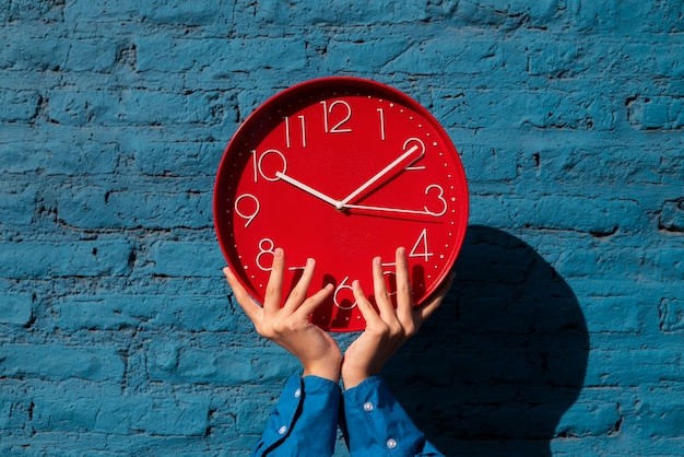 Free photo hands holding wall clock still life