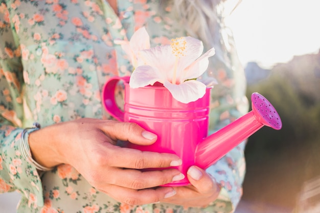 Hands holding a watering can with a decorative flowers