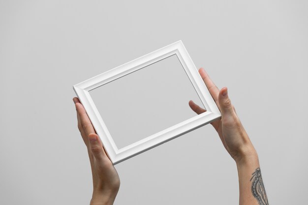 Hands holding white wooden frame