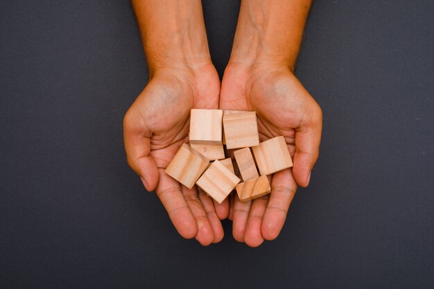 hands holding wooden cubes.