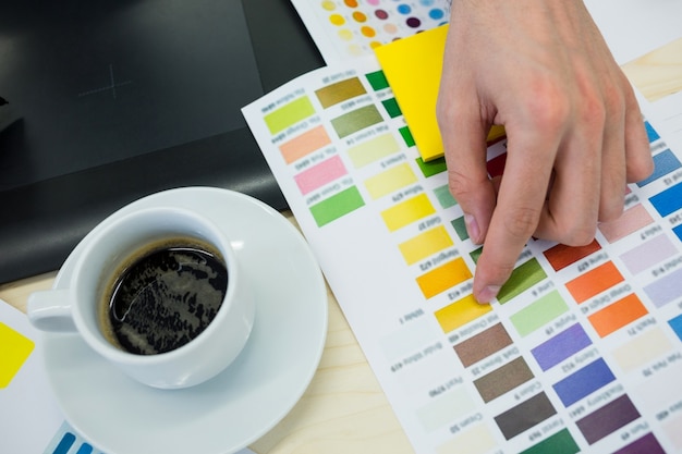 Free photo hands of male graphic designer choosing color from color chart