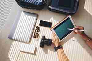 Free photo hands of man looking at business calendar on tablet, and suitcase with electronic devices nearby