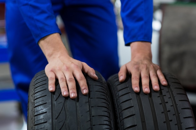 Free photo hands of mechanic touching tyres