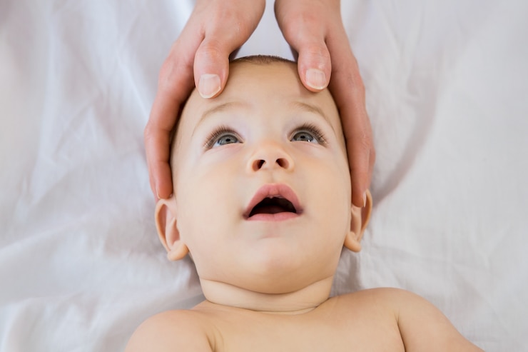 Free Photo hands of a mother touching head of her baby boy