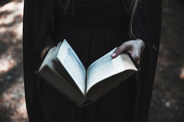 Бесплатное фото Руки женщины в черном платье с открытой книгой
