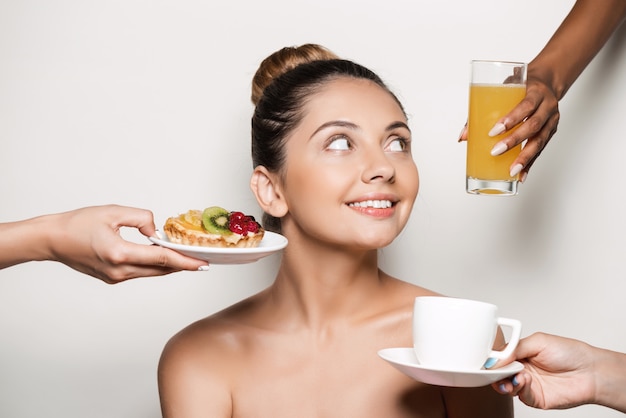 Hands offering cake and drinks to young beautiful woman