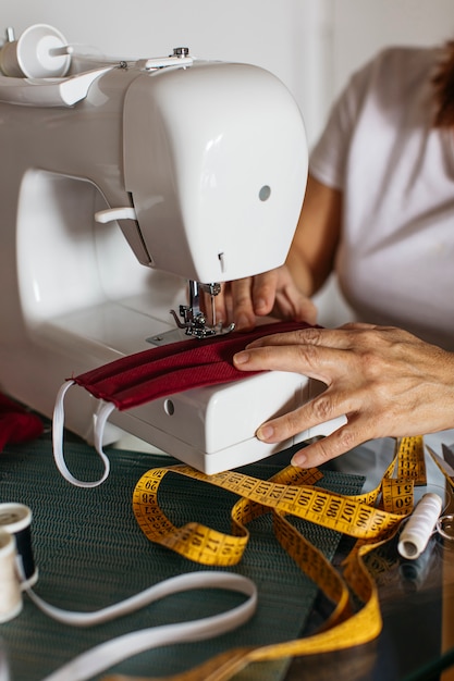 Free photo hands of old woman sewing cloth face masks for friends