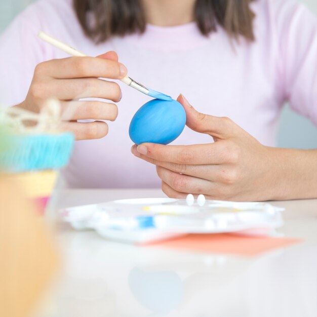 Hands painting egg at table