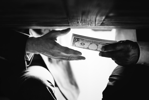 Руки передают деньги под стол коррупции и взяточничества