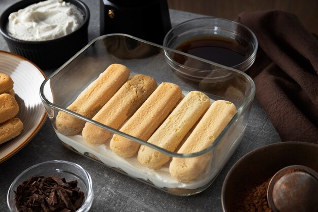 Hands pouring coffee over ladyfingers