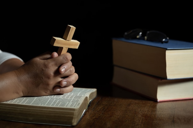 Free photo hands praying to god while holding the cross symbol.