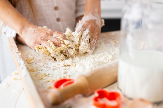 Руки готовят тесто рядом с кухонным роликом