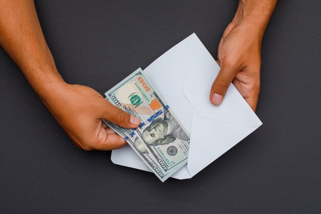 hands putting banknotes in envelope.