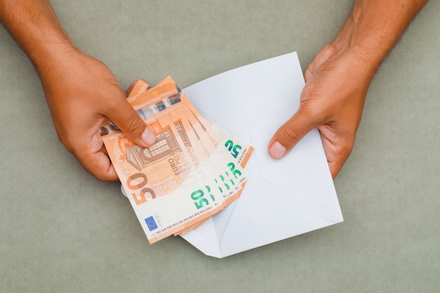 hands putting banknotes in envelope.