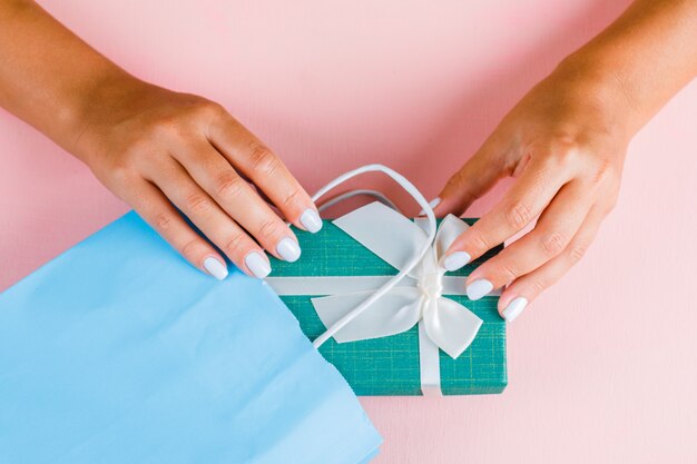 Hands putting gift box into paper bag