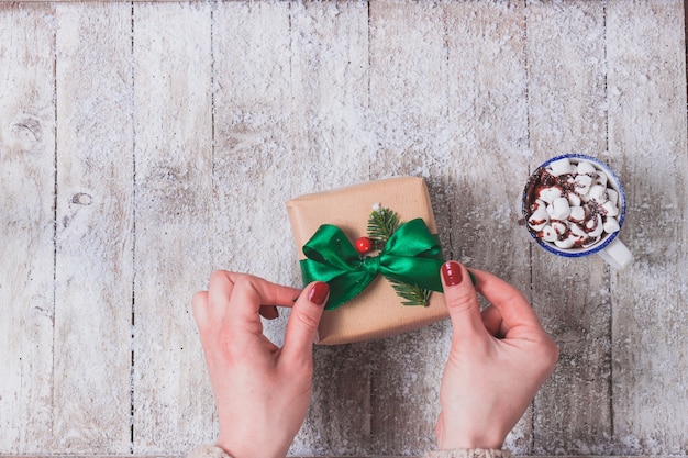 Hands putting a green bow on a gift