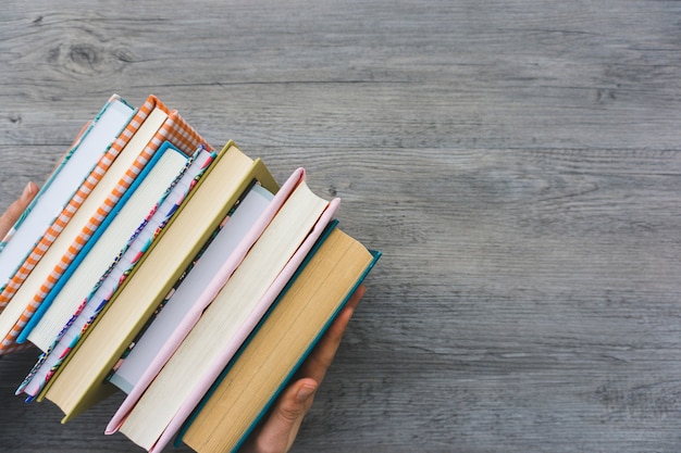 Hands putting some books on wooden surface