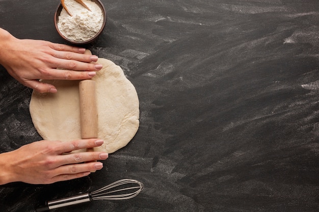Hands rolling bread dough with whisk