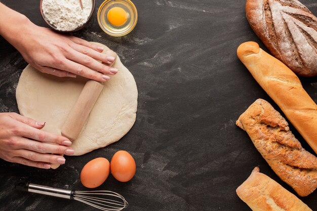 Hands rolling dough with eggs and whisk