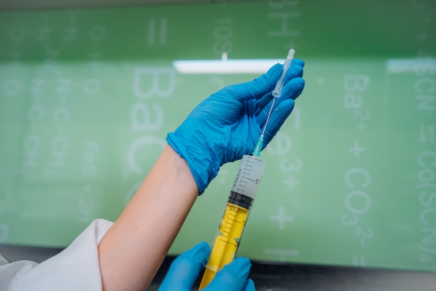 Hands in rubber gloves hold a disposable medical syringe with the drug