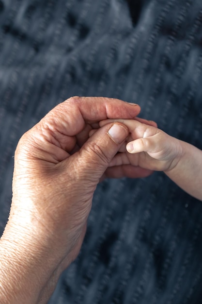 Free photo hands of senior person and little baby close up