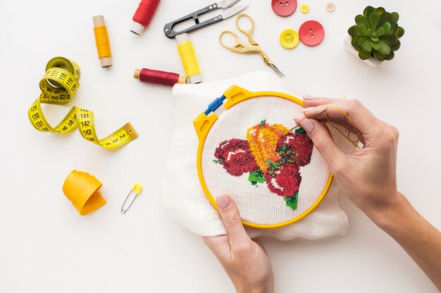 Hands sewing a cute fruit design on white background