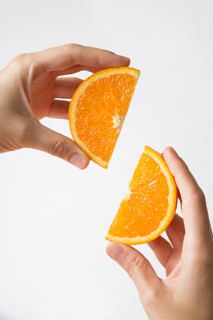 Free photo hands showing couple of cut juicy orange sections