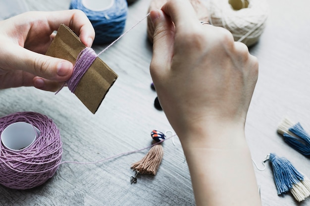 Hands spooling thread on carton