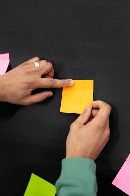 Hands sticking yellow post it on board