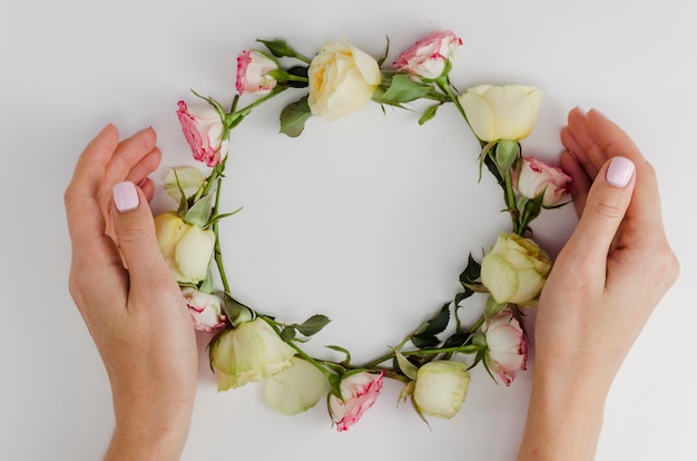 Free photo hands surrounding round rose frame