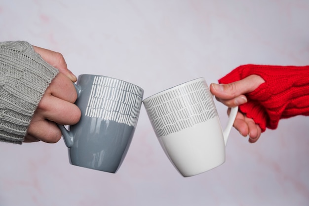 Free photo hands in sweaters clinking mugs