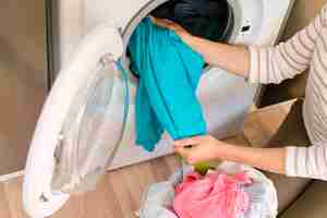 Free photo hands taking laundry out washing machine