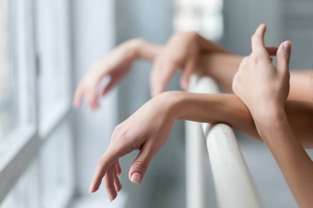 Hands of two classic ballet dancers at barre