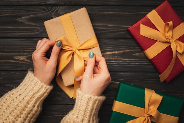 Hands tying golden ribbon on present