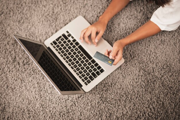 Hands typing and holding a credit card on floor