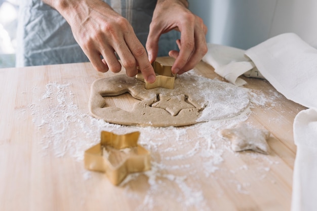 Hands using cookie cutter on dough