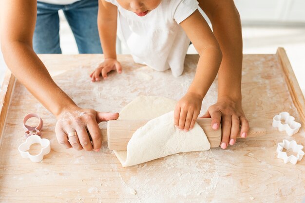 Руки с помощью кухонного валика на тесте для печенья