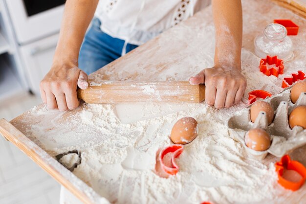 Hands using kitchen roller to make dough