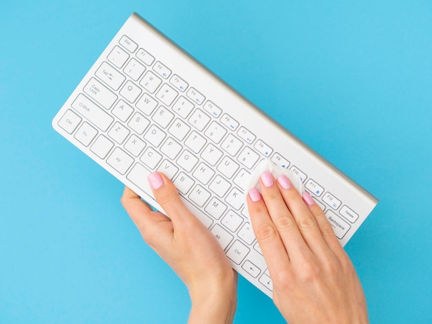 Hands using napkin to clean keyboard