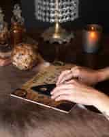 Бесплатное фото Руки с помощью доски для спиритических сеансов под высоким углом