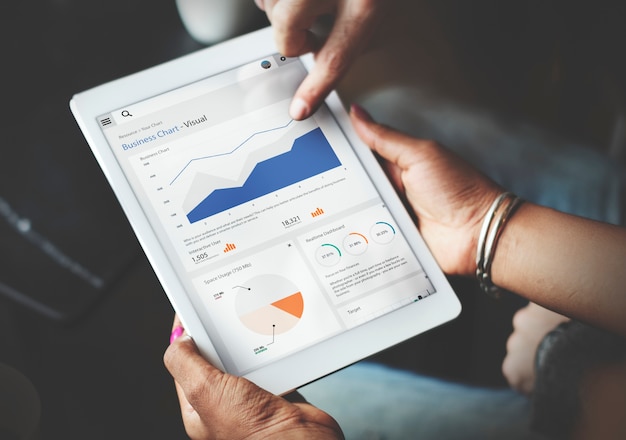 Mani facendo uso dello schermo della compressa che mostra i dati di affari di statistiche